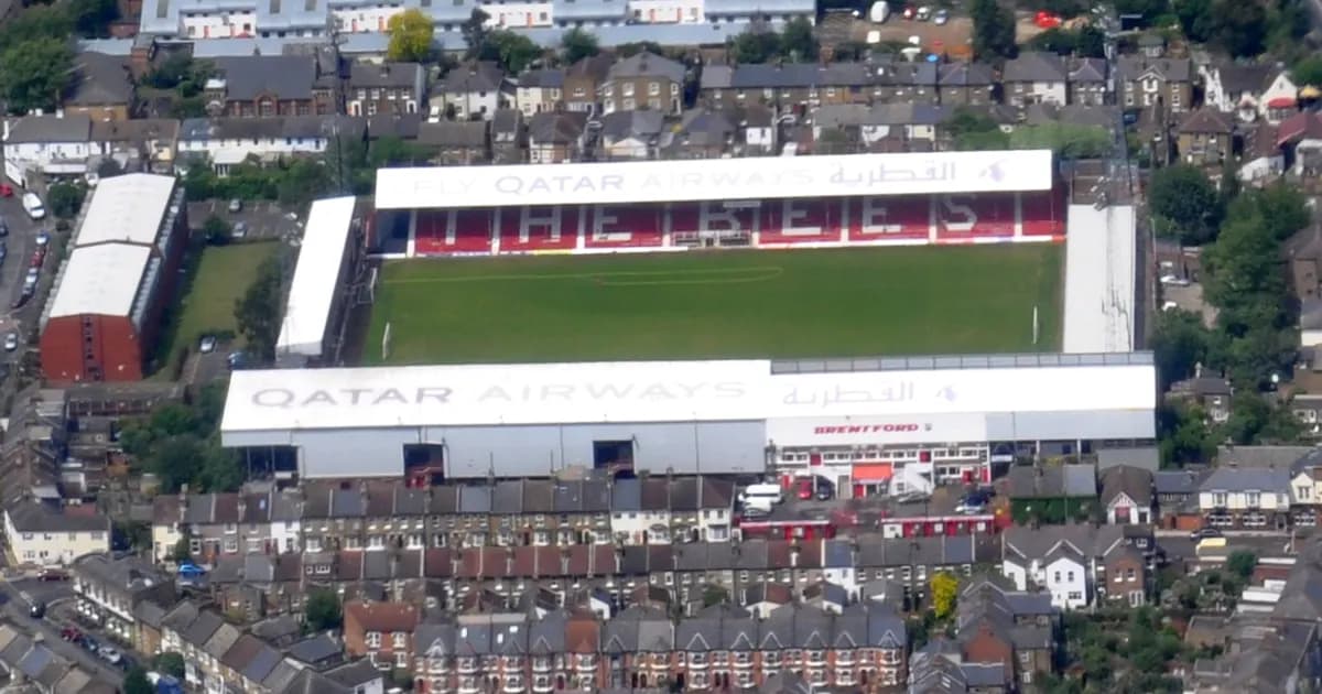 General view of a football stadium's pitch and stands before kickoff, with empty seats and floodlights on ahead of a Premier League match.